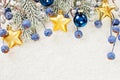 Christmas border of gold star decor, green fir branch, blue berries and baubles on winter white snow background. Xmas and New Year Royalty Free Stock Photo