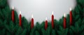 Christmas border made of evergreen branches decorated with burning candles