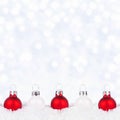 Red and white Christmas ornaments in snow with a twinkling silver light background Royalty Free Stock Photo