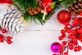 Christmas border with white silvery cones, bright Christmas decorations and red Butcher`s Broom flower on a white background Royalty Free Stock Photo