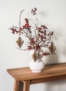 Christmas bouquet on a wooden table. Cranberry Branches with paper craft Christmas toys in a ceramic vase