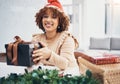 Christmas, box and portrait with a black woman teacher giving a gift at her desk in a school in a classroom. December