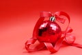 Red toy ball for the Christmas tree with a red ribbon on a red background Royalty Free Stock Photo