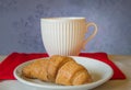 Christmas Breakfast - White Cup and croissant on a background of red knitted scarf