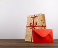 Christmas Brown Paper Bag with Ribbon and a Red Envelope on wooden table isolated on white background Royalty Free Stock Photo