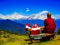 Christmas a buddhist monk sitting on a bench with his santa claus hat and bag full of presents next to him