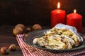 Christmas cake, german christstollen with fruits, raisins and marzipan in front of two red candles and nuts on rustic dark wood Royalty Free Stock Photo