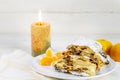 christmas cake, german christstollen with tangerines and a burning candle against a white wooden background with copy space