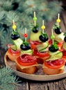 Christmas canape on skewer from bread baguette with toast cheese, sausage, tomato, cucumber and olives. Traditional snack for the