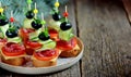 Christmas canape on skewer from bread baguette with toast cheese, sausage, tomato, cucumber and olives. Traditional snack for the