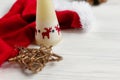 Christmas candle with deers and golden star and santa hat on wh