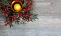 Christmas Candle with Evergreen Tree Branches and Berries Over Rustic Wood Royalty Free Stock Photo