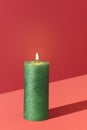 Christmas candle isolated on a red background. Burning green candle Royalty Free Stock Photo