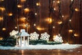 Christmas candle lantern and Christmas tree branches, snow, snowflake and decorations on bokeh background blurred lig