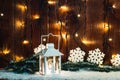 Christmas candle lantern and Christmas tree branches, snow, snowflake and decorations on bokeh background blurred lights Royalty Free Stock Photo