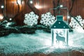 Christmas candle lantern and Christmas tree branches, snow, snowflake and decorations on bokeh background blurred lig Royalty Free Stock Photo