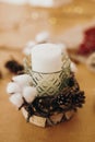 Christmas candle in rustic holder made of branches, cotton, anise and pine cones on wooden table with festive lights. Holiday Royalty Free Stock Photo