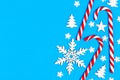 Christmas candy cane lied evenly in row on blue background with decorative snowflake and star. Flat lay and top view Royalty Free Stock Photo