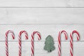 Christmas candy canes and Christmas tree on white wooden background