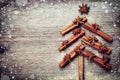 Christmas card with Christmas fir tree made from spices cinnamon sticks, anise star and cane sugar on rustic wooden background