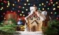 Christmas card with decorative toy house with pine branches, gifts on garland bokeh background. Royalty Free Stock Photo