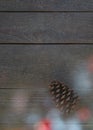 Christmas card with a fir cone and beautiful christmas lights in front of a wooden background