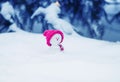 Christmas card with a funny toy snowman in a bright pink cap sitting in a snowdrift with a gift under the tree Royalty Free Stock Photo