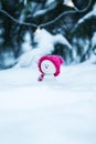 Christmas card with a funny toy snowman in a bright pink cap sitting in a snowdrift with a gift under the tree Royalty Free Stock Photo