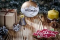 A gift lays on a wooden table next to a candle, cones and an angel against the background of Christmas decorations Royalty Free Stock Photo