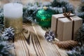 A gift lays on a wooden table next to a candle, cones and an angel against the background of Christmas decorations Royalty Free Stock Photo