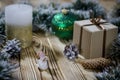 A gift lays on a wooden table next to a candle, cones and an angel against the background of Christmas decorations Royalty Free Stock Photo