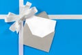 Christmas Card With Gift Ribbon Bow In White Satin On Blue Paper Background