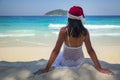 Christmas card, girl in a Santa Claus hat on a beautiful beach by the sea