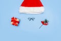 A Christmas card made of a Santa Claus hat, Santa glasses, a New Year\'s gift, branches of a fir tree on a blue background.