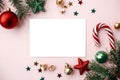 Christmas card mockup. Empty greeting card flat lay with red christmas decorations, fir branches and ornaments on pink background Royalty Free Stock Photo