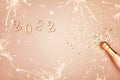 Christmas card with pink golden champagne bottle, confetti stars and 2022 numbers. Flat lay. Celebration background for New Year Royalty Free Stock Photo