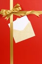 Christmas card, red gift background, gold ribbon bow, envelope, white copy space, vertical Royalty Free Stock Photo