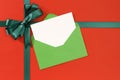 Christmas card, red gift wrap paper background, green gift ribbon bow, envelope, copy space Royalty Free Stock Photo