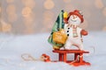 Christmas card with red wooden Santa Claus sleigh with snow man, and Xmas tree balls over blurred light background Royalty Free Stock Photo