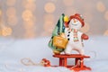 Christmas card with red wooden Santa Claus sleigh with snow man, and Xmas tree balls over blurred light background. Royalty Free Stock Photo