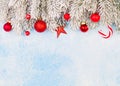 Christmas Card. Red Xmas Decorations And Green Winter Frozen Fir Branches On Blue Frozen Stucco Texture Background