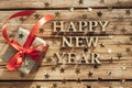 Christmas card with text, banner Happy New Year. Brightly lit letters and a gift on a wooden background. Selective focus