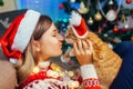 Christmas celebration with cat. Woman playing and kissing pet in Santa`s hat by New year tree at home Royalty Free Stock Photo