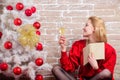 Christmas celebration concept. Christmas eve. Noel and joy. Girl in red dress relaxing with glass of champagne near