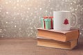 Christmas celebration with cup and gift box on books over bokeh background