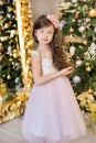 Christmas celebration. Cute little girl in a beautiful dress sitting near the Christmas tree. Christmas miracles. Luxurious Christ Royalty Free Stock Photo
