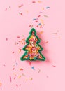 Christmas celebration flat lay with toy christmas tree and sprinkle on pink background