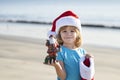 Christmas child holiday concept. Santa kid on the sunset sea. Summer hot New Year. Sea background, holiday concept Royalty Free Stock Photo