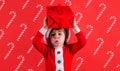 Christmas child with present. Santa helper with gift box. Kid boy in Santa costume. New year advertising.