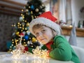 Christmas child writes a letter to Santa while sitting at the table against a bokeh background